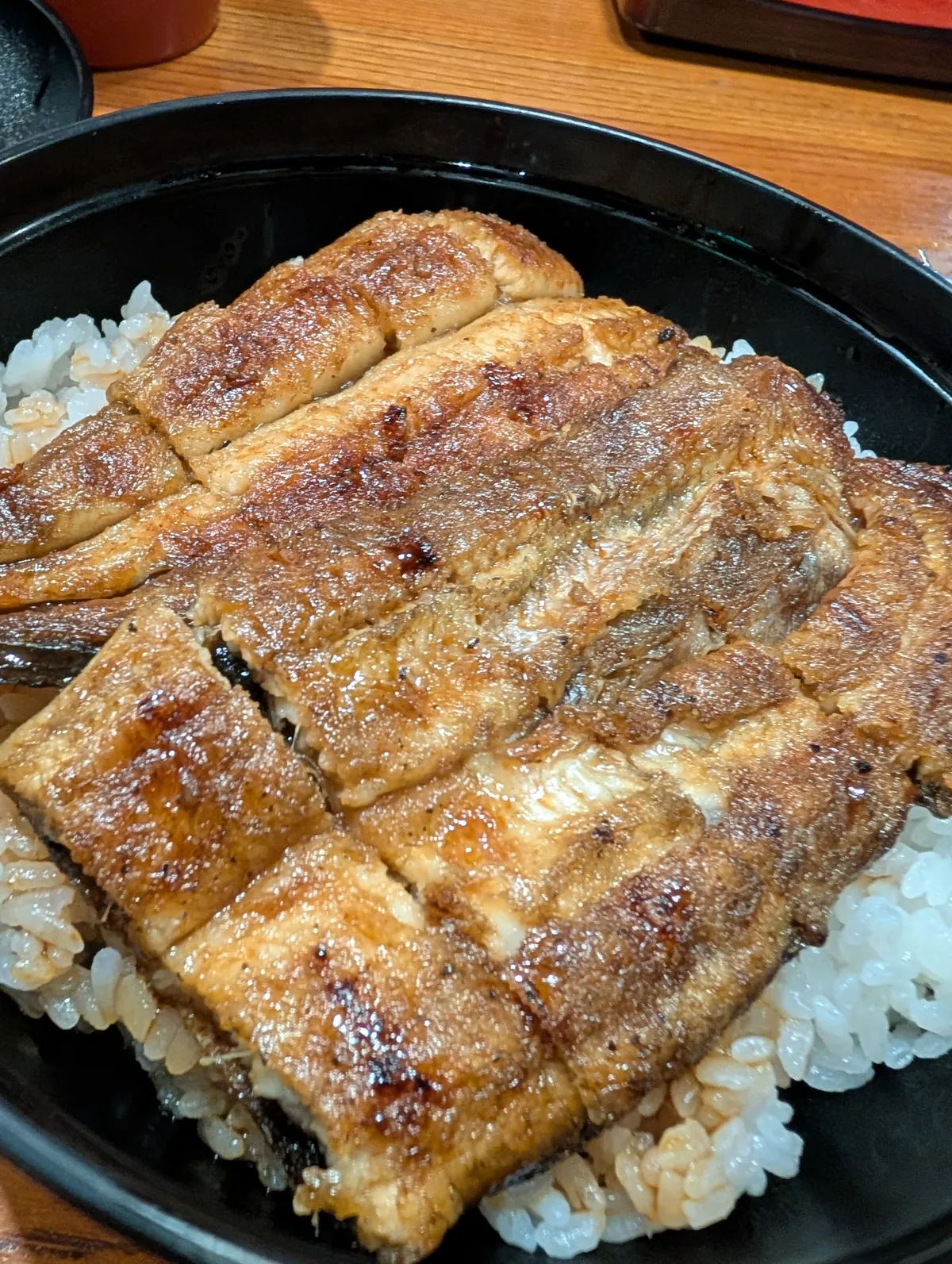 A donburi-style unagi bowl with glossy lacquered eel slices on rice, served at a Gifu eel specialty restaurant