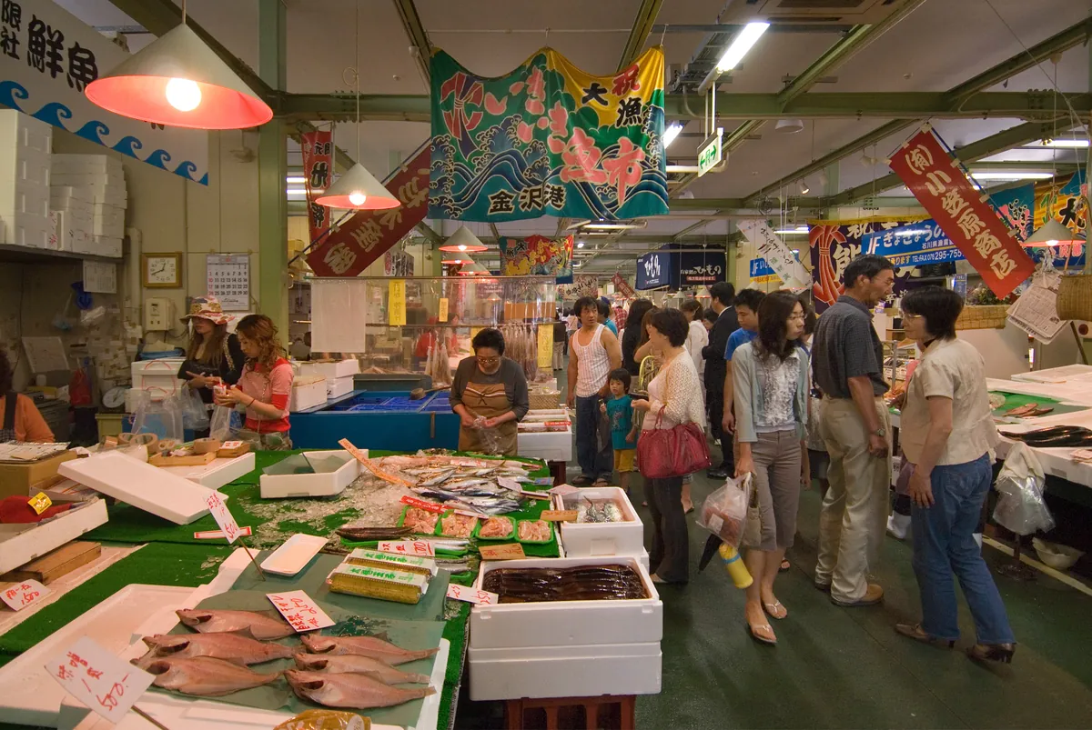 Bustling seafood stalls with colorful banners at Omicho Market — Kanazawa's Kitchen