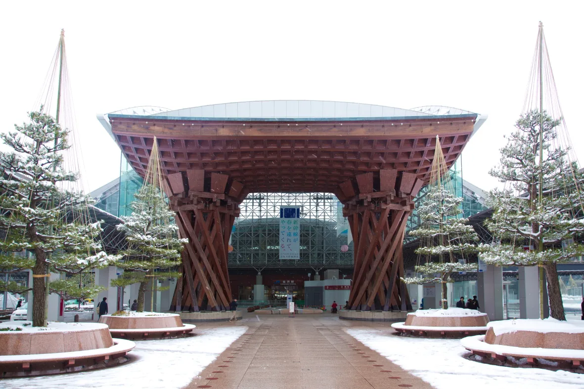 The massive wooden Tsuzumi Gate at Kanazawa Station framed by snow-covered pine trees