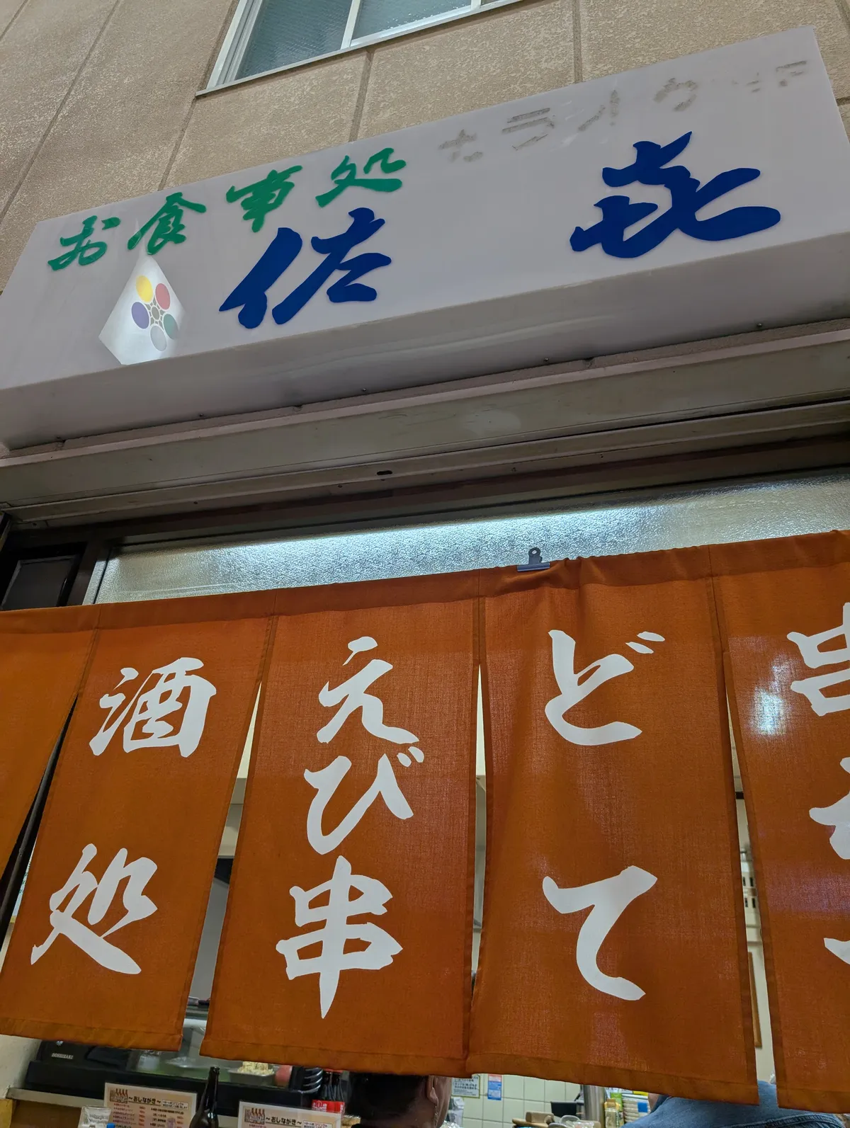 Traditional izakaya entrance with noren curtains advertising doteni and ebi-kushi