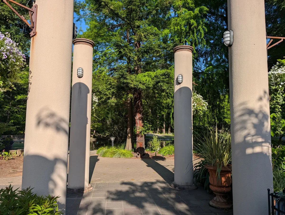 A line of white round columns in a colonnade at Flarie, with the garden visible between them