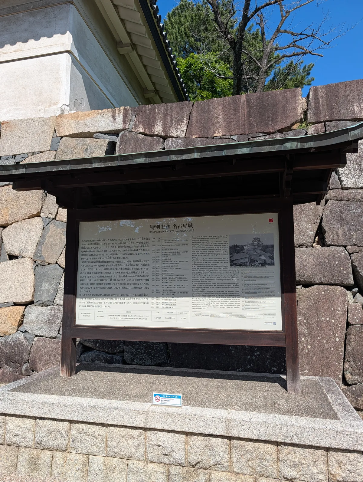 An interpretive panel about the nozurazumi wild-piling stone wall technique, set against the original 400-year-old stones of Nagoya Castle