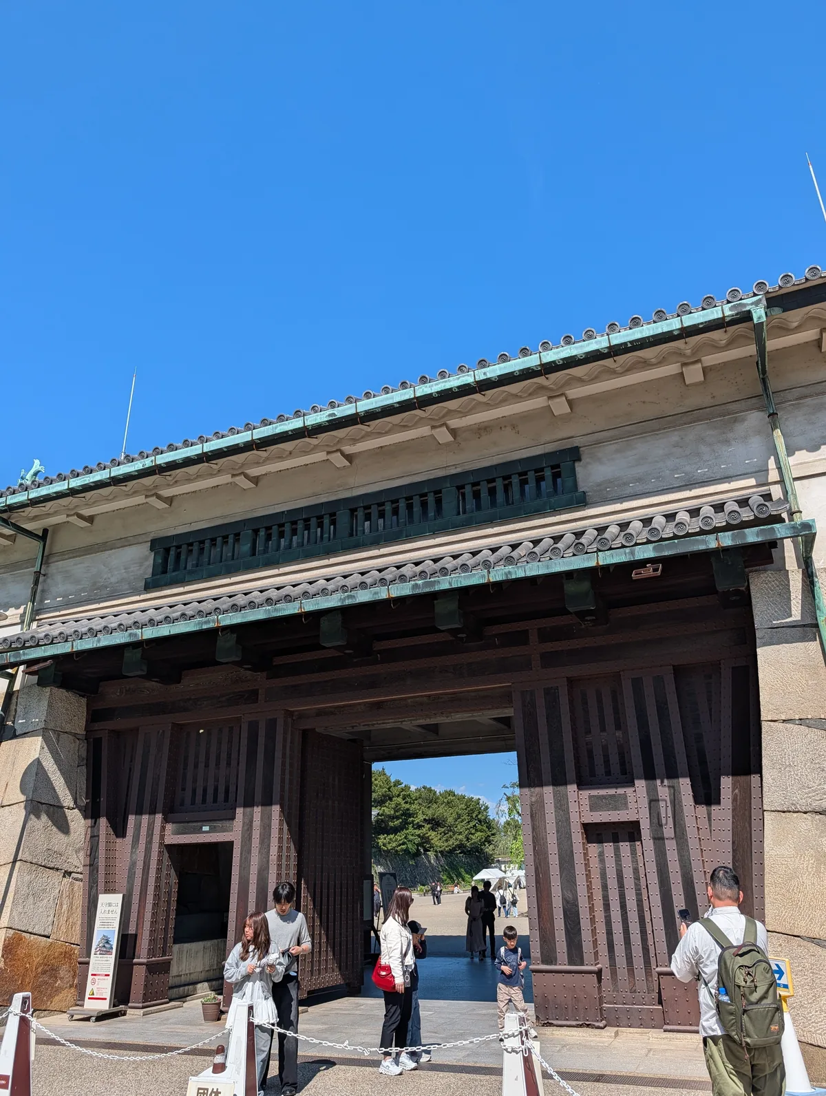 Nagoya Castle main gate (Omotemon) framed against a deep blue May sky, with visitors walking through