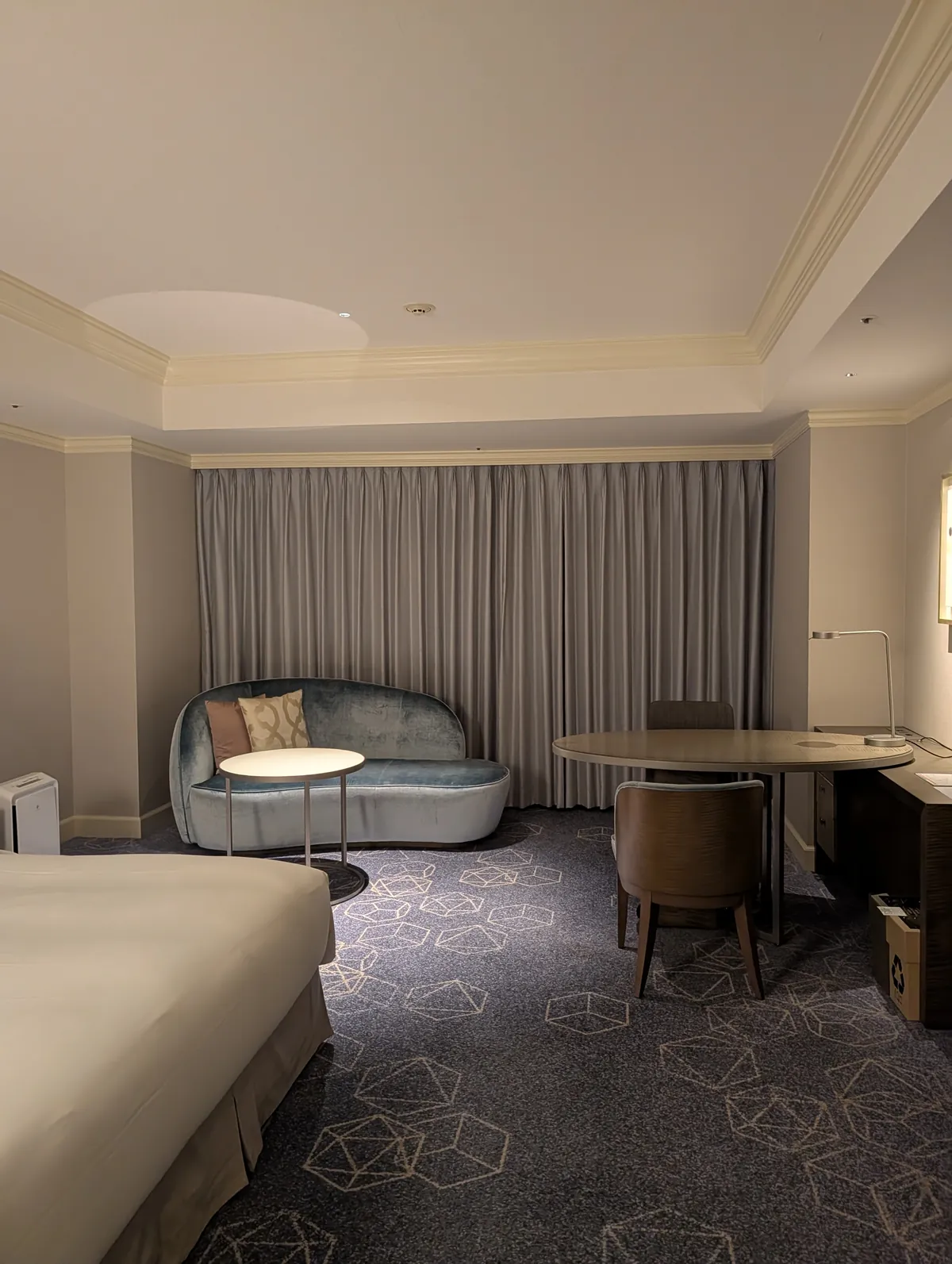 High-floor guest room at Nagoya Marriott Associa Hotel with a king bed, a curved teal velvet sofa, and a round work desk