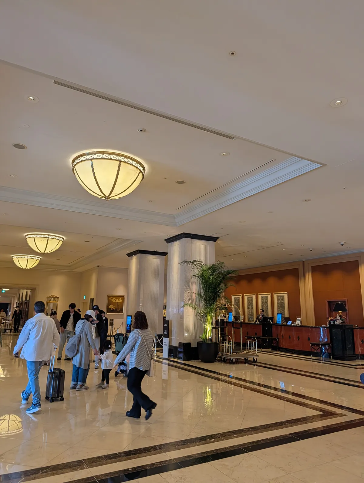 Marble-floored lobby of Nagoya Marriott Associa Hotel with classical hanging light fixtures and check-in counter visible at the back