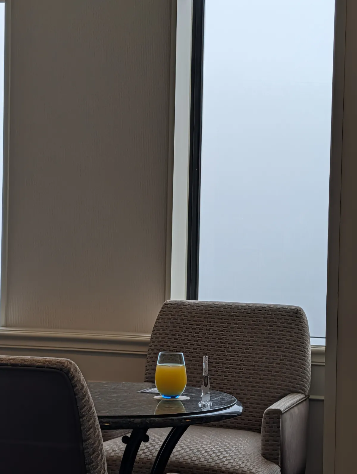 A morning glass of orange juice on a marble-topped table by the window inside the Marriott Associa executive lounge