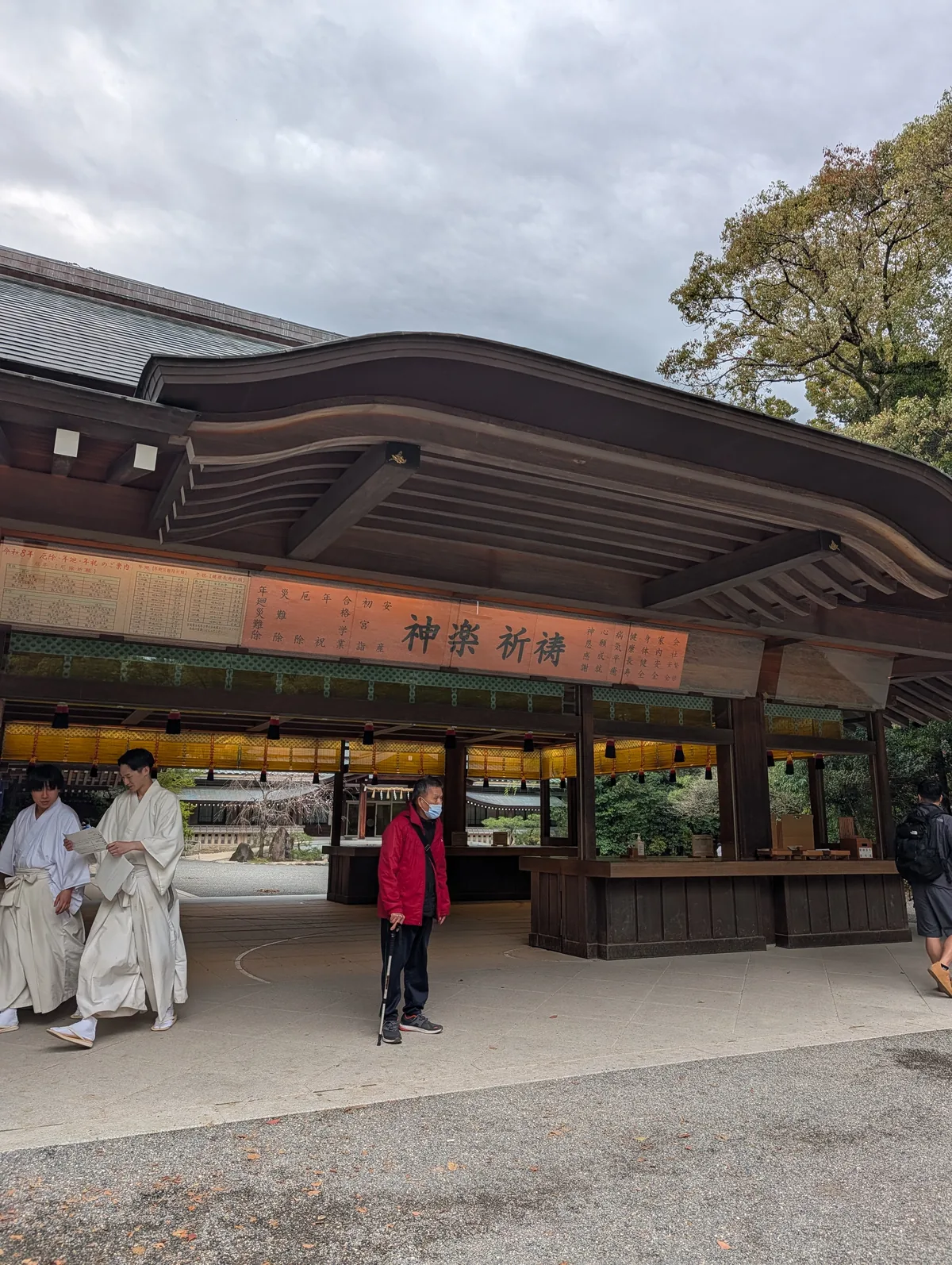The kagura prayer hall at Atsuta Shrine with a red sign reading kagura kito and priests in white robes standing outside