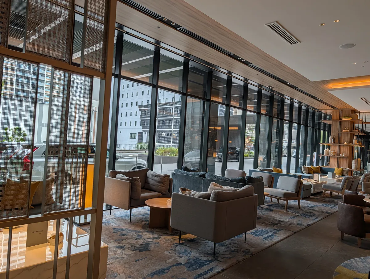 THE LOUNGE on the first floor of Courtyard by Marriott Nagoya, with a full-height glass wall, low sofas, a blue carpet and a Courtyard sign at the right